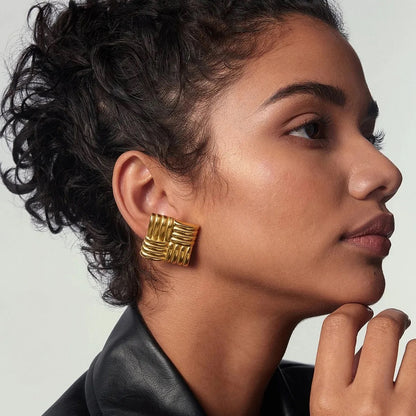 Women with a pair  of Retro Gold Statement Stud Earrings. They are square-shaped with a woven design and are gold-plated.