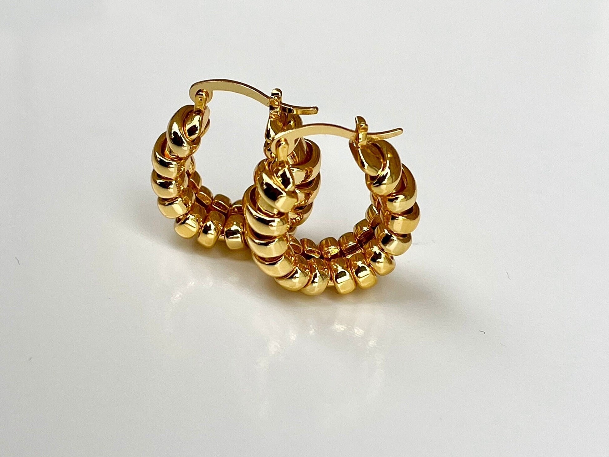 Pair of elegant gold-toned hoop earrings with a unique coiled or ribbed textured design.