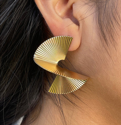 Women wear a pair of Spiral Abstract Fan Shaped Earrings. They are fan-shaped with a spiral design and appear to be made of gold-toned metal.