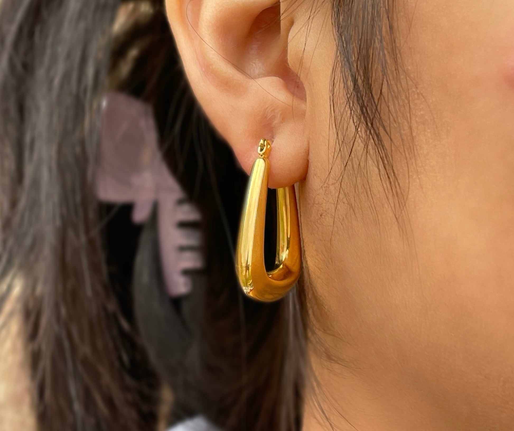 Large, gold-colored hoop earrings with a slightly oval shape.